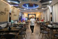 um homem caminhando por um restaurante com um prato de comida em Hotel Smile em Kobuleti