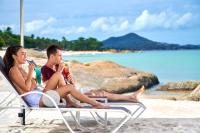 two people sitting in chairs on the beach at Sheraton Samui Resort in Chaweng Noi Beach
