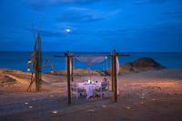 a dinner table on the beach at night at Sheraton Samui Resort in Chaweng Noi Beach