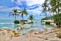 a resort swimming pool with palm trees and the ocean at Sheraton Samui Resort in Chaweng Noi Beach