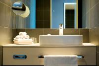 a bathroom with a sink and a mirror and towels at Atlantic Hotel Sail City in Bremerhaven