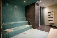a bathroom with a green tiled shower and a toilet at Atlantic Hotel Sail City in Bremerhaven