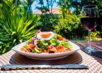 Een salade met een ei op een bord naast een glas wijn. bij Pavillon d'Orient Boutique Hotel in Siem Reap