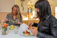 duas mulheres sentadas numa mesa com um prato de comida em Hotel Das Bayerwald em Lam