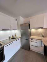 a kitchen with white cabinets and a stainless steel refrigerator at Chic &amp; moderne appartement - proximité métro in Asnières-sur-Seine