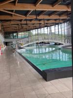 a large swimming pool with green water in a building at F1 noir&#47;anis, avec terrasse couverte et jardin (E) in Compreignac