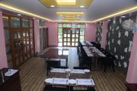 comedor con mesas, sillas y paredes rosas en Hotel Gridhakuta International, en Rajgir