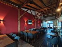 a restaurant with red walls and wooden tables and chairs at Hostel am GÜTERBAHNHOF in Neubrandenburg