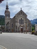 an old church with a clock tower on a street at La petite Anfiane in Le Grand-Bornand