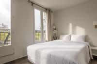 a white bedroom with a large bed and a window at Hotel Beauvoir in Paris
