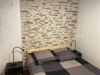a bed in a room with a stone wall at T2 Le Conquet &quot;Molène&quot; avec parking privé 300m commerces in Le Conquet