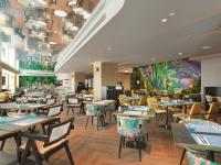 Un restaurante con mesas y sillas y un mural. en NYX Hotel Limassol, en Limassol