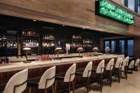 Un bar en un restaurante con sillas blancas y botellas de licor. en The Central Station Memphis, Curio Collection By Hilton, en Memphis