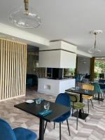 Un comedor con mesas y sillas y una cocina. en Hôtel Restaurant du Lac, en Boussens