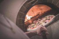 Iemand steekt zijn hand in een pizzaoven. bij Ahrner Wirt Apartments in San Giovanni in Val Aurina