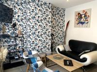 Una sala de estar con un sofá negro y una mesa. en Le P&#39;tit Cocon, en Calais
