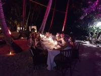 a group of people sitting at a dinner table at night at Batuta Maldives Inn in Thulusdhoo