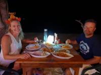 a man and a woman sitting at a table with food at Batuta Maldives Inn in Thulusdhoo
