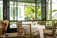 a dining room with a table and chairs and windows at Hôtel Eldorado Paris in Paris