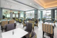 a restaurant with tables and chairs and windows at Hilton Garden Inn Halifax Airport in Enfield
