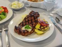 a white plate with meat and vegetables on a table at The Hilton Garden Inn Buffalo-Downtown in Buffalo