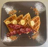 Un plato con waffles y tocino y waffles con plátanos en Real Hispano, en Valladolid