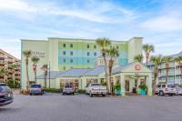 a hotel with palm trees and cars parked in a parking lot at Hilton Garden Inn Orange Beach in Orange Beach
