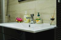 a bathroom sink with two bottles of soap and a flower at Apartman Stil in Bugojno