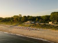 a row of barrels on a beach next to the water at Weissenhaus Private Nature Luxury Resort in Weißenhaus
