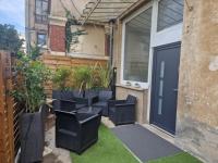 a patio with black chairs and a garage door at appartement cosy en centre ville avec terrasse in Villefranche-sur-Saône