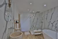 a bathroom with a tub and a marble wall at Gîte Louannec - Ty Bleiz in Louannec