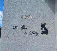 un panneau avec un chien sur le côté du bâtiment dans l&#39;établissement Le Gîte de Daisy, à Saint-Côme-du-Mont