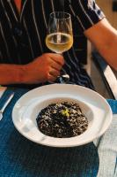 Hotel Štacija في قشتيلا: رجل يحمل كأسًا من النبيذ بجانب طبق من الطعام