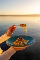 Hotel Štacija في قشتيلا: شخص يحمل طبقًا من المعكرونة مع قطعة طعام