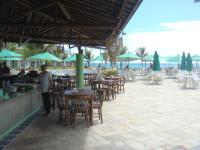 Ein Mann steht vor einem Restaurant mit Tischen und Stühlen in der Unterkunft Ancorar Porto de Galinhas flat 7205 in Ipojuca