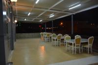 una fila di tavoli e sedie su un balcone di notte di NUS GRAND HOTEL a Çatalözü