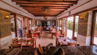 a restaurant with wooden tables and chairs and windows at Maria Bonita Hotel in Villa de Leyva