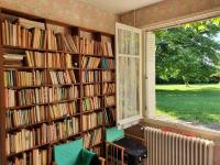 a library with shelves filled with books and a window at Le Grand Libois - ancienne ferme 