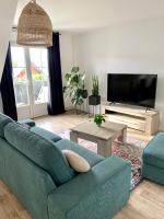 a living room with a blue couch and a tv at Appartement NATURA 2 chambres in Vitré