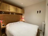 a bedroom with a white bed and wooden cabinets at Alpe d&#39;Huez Houses - Chalet des Roches - Duplex, SUR les pistes de 3 chambres ! in LʼHuez