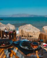 a table with a plate of food and a glass of wine at Aphrodite Beach in Kissamos