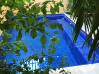 una piscina azul con un árbol en el primer plano en Hotel Las Salinas, en Zihuatanejo