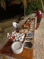 a long buffet of food on a table on the beach at The Sunset Villa in Dhiffushi