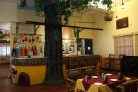 Un restaurante con un árbol en medio de una habitación. en Ramanashree California Resort, en Yelahanka