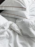 ein unmaskiertes Bett mit weißer Bettwäsche und Kissen in der Unterkunft Mana Sleep &amp; Spa in Druskininkai