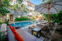 Un patio al aire libre con mesa y sombrilla y una piscina. en Pondok Sari Kuta, en Kuta