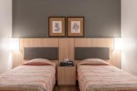 a bedroom with two beds and two pictures on the wall at DELPLAZA Timbiras São Paulo in São Paulo