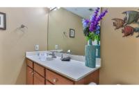 ein Badezimmer mit einem Waschbecken und einer Vase mit lila Blumen in der Unterkunft Beach Resort 507 - Great Views Beautiful Decor Zero Entry Pool in Destin