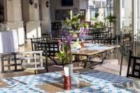 Un restaurante con mesas y sillas con flores en un jarrón. en Sentrim Castle Royal Hotel, en Mombasa