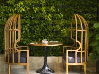 duas cadeiras e uma mesa em frente a uma parede verde em MerPerle Crystal Palace em Cidade de Ho Chi Minh